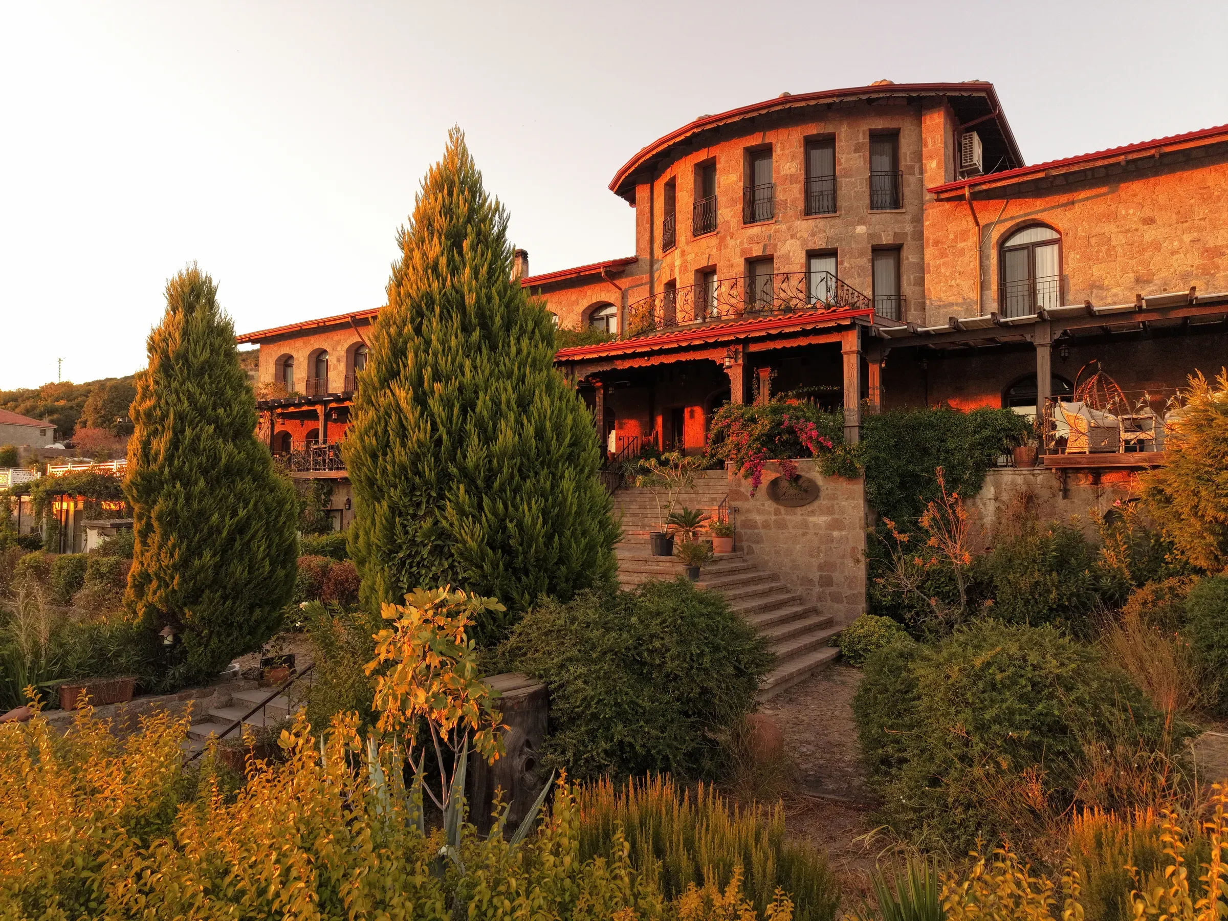 Gün batımında taş otel binası ve bahçe merdivenleri
